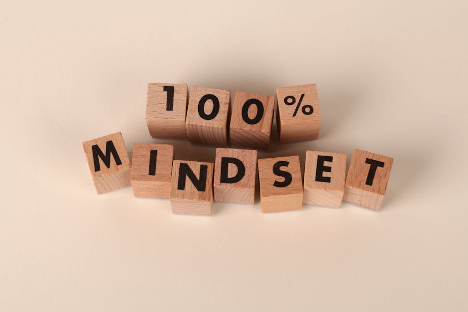 Wooden blocks arranged to spell '100% Mindset' on a neutral beige background, promoting positivity.