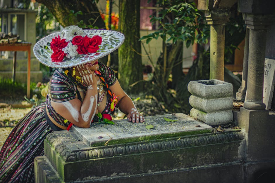 A woman in traditional Catrina attire at a cemetery during Day of the Dead in Mexico City.