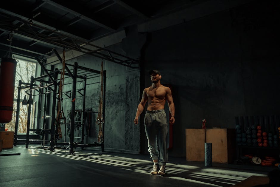 A muscular man poses confidently in a dimly lit gym, highlighting his toned physique.
