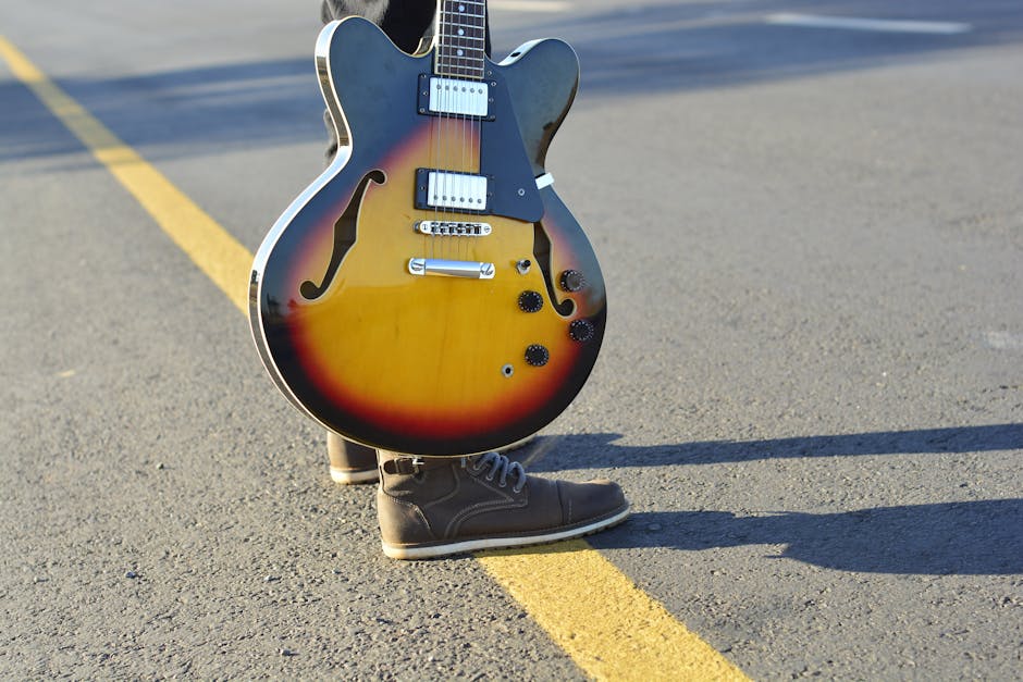 Stylish electric guitar with bright finish resting on asphalt road with yellow line.